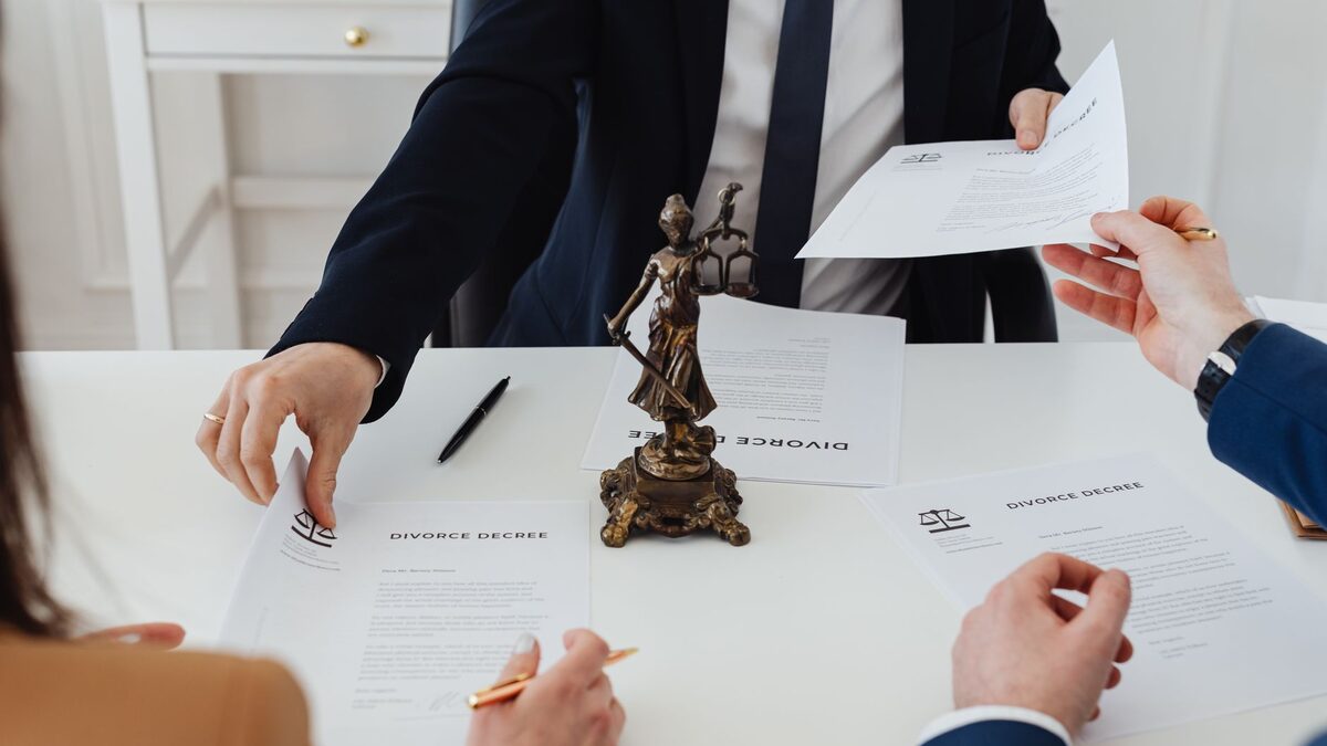 Three adults discussing divorce documents in a formal office setting with legal statue in view.