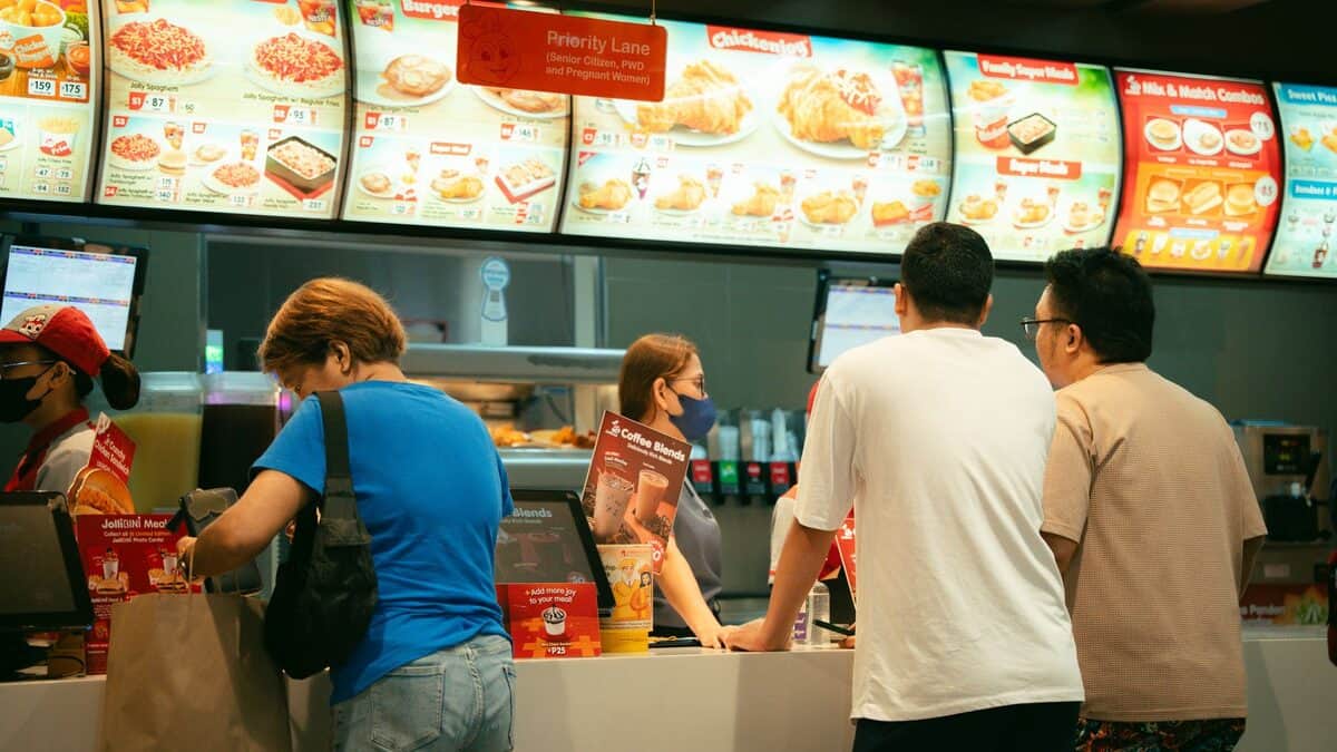 Customers ordering food at a fast food restaurant counter. Busy atmosphere.